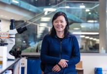 Dr. Hongkui Zeng smiling next to a microscope at the Allen Institute.